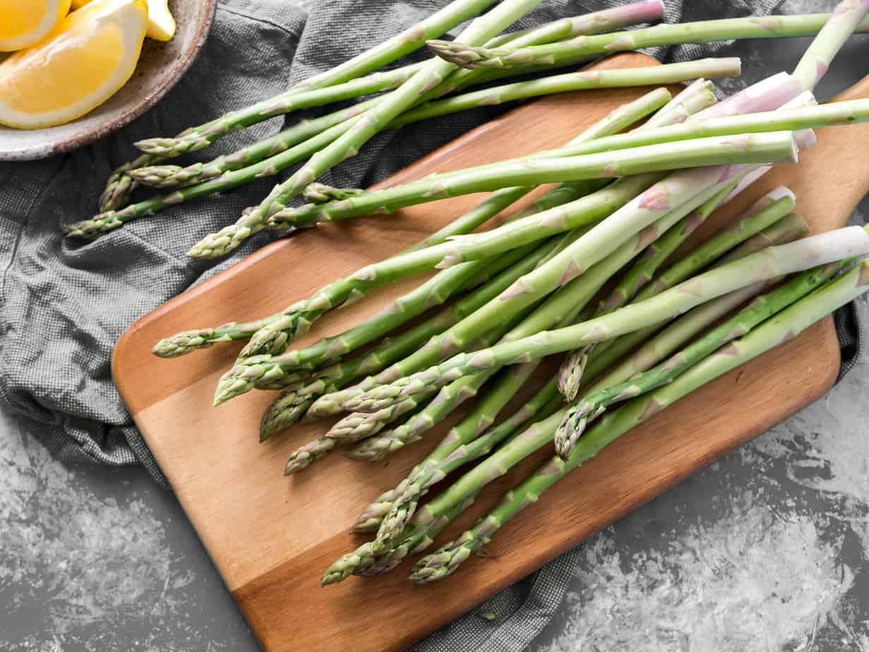 raw asparagus on a wooden cutting board