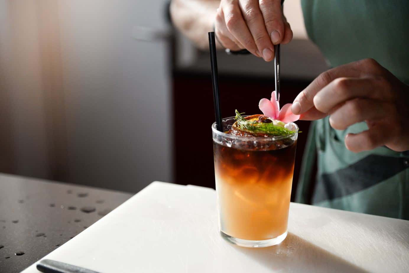 carribean screwdriver cocktail with fresh garnish being stirred.