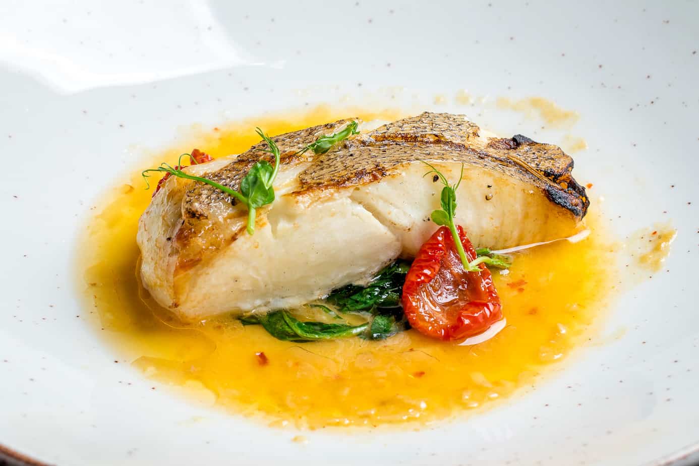 get gourmet with your micro wedding menu. A piece of pan seared seabass with a saffron sauce and blistered tomato