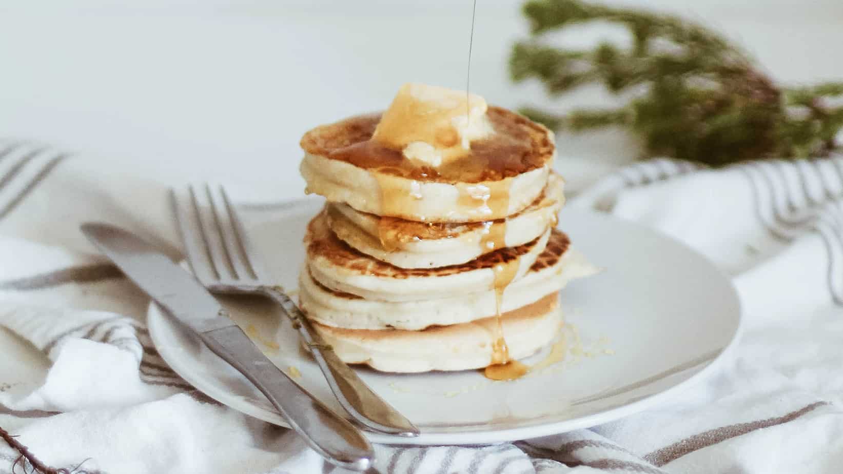 fluffy gluten free pancakes being drizzled with maple syrup