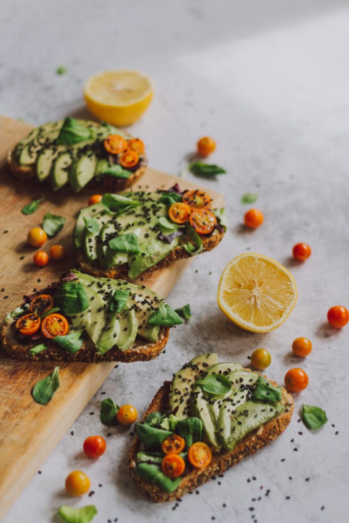 Avocado toast for brunch consisting of toasted whole grain bread, organic avocado, fresh baby spinach, and chili flakes