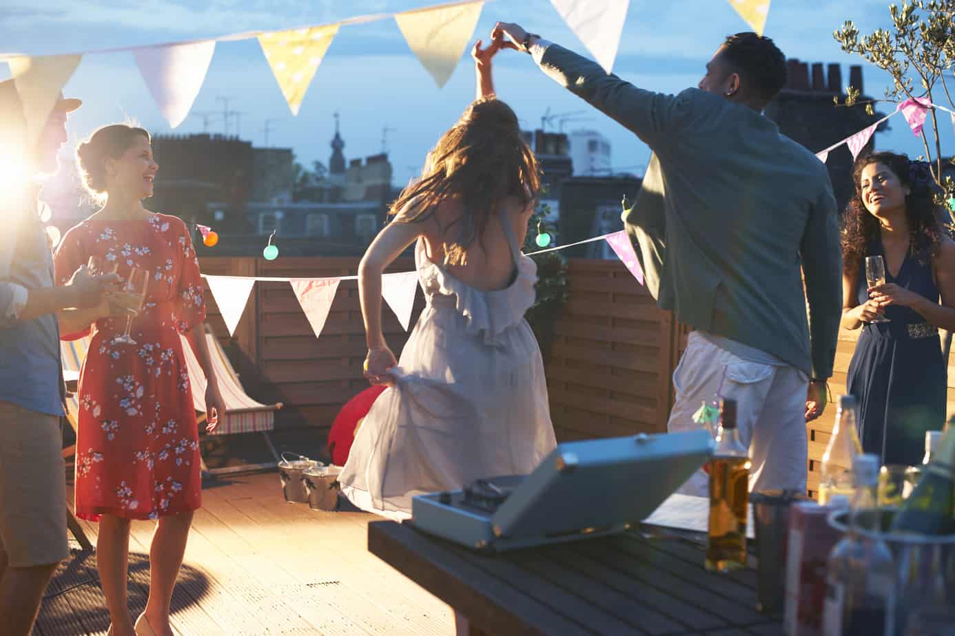 friends on a rooftop deck enjoying cocktails and dancing 