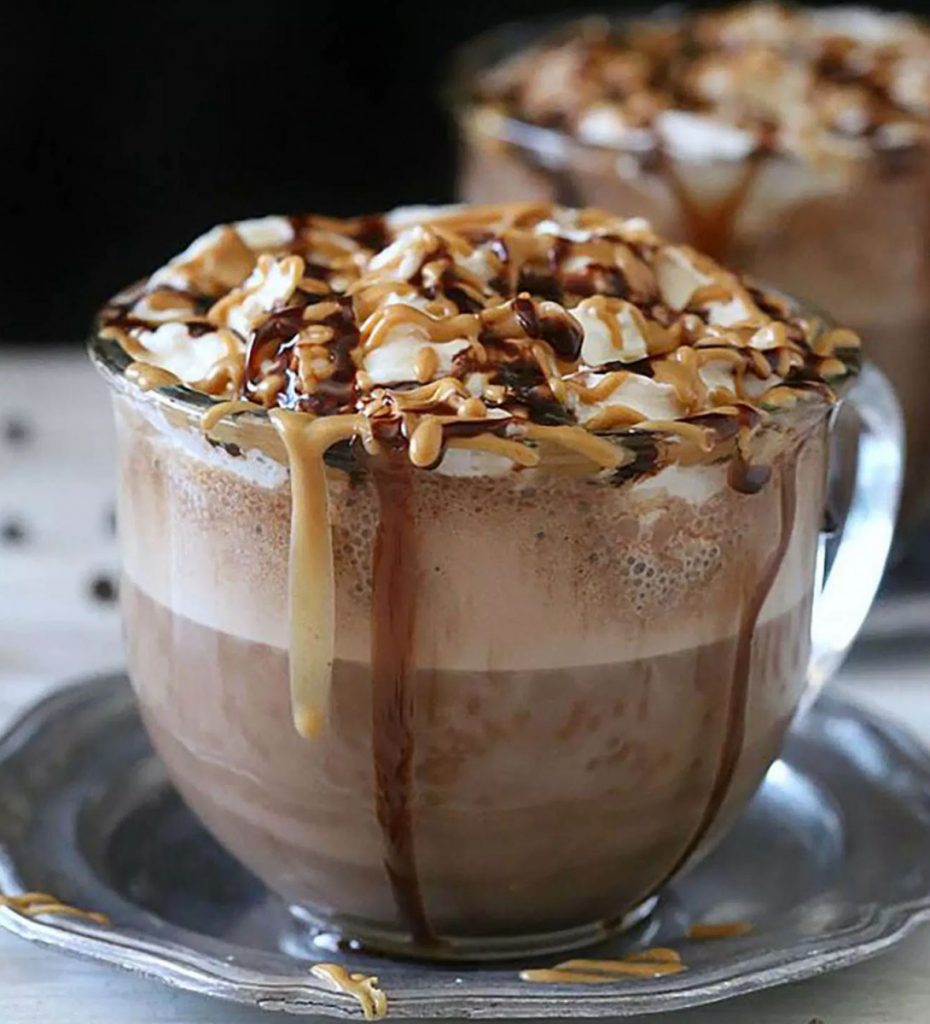 mug of gourmet hot chocolate with caramel and chocolate drizzle on top of whipped cream