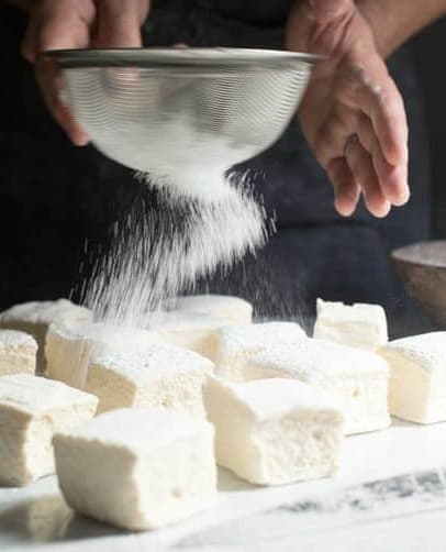 dusting homemade marshmallows with powdered sugar