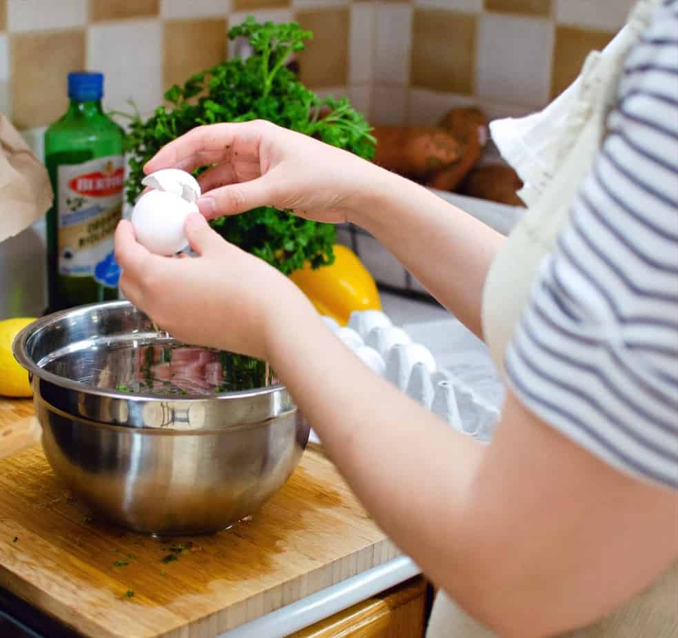 a child cracking an egg into a bowl