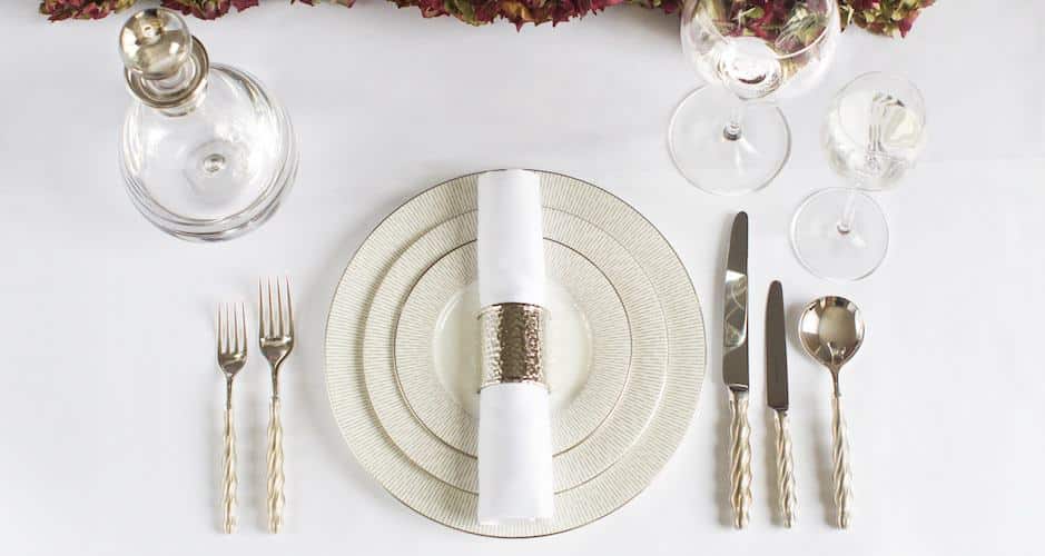 a very elegant formally set dinner table with luxury china, silverware, and glassware.