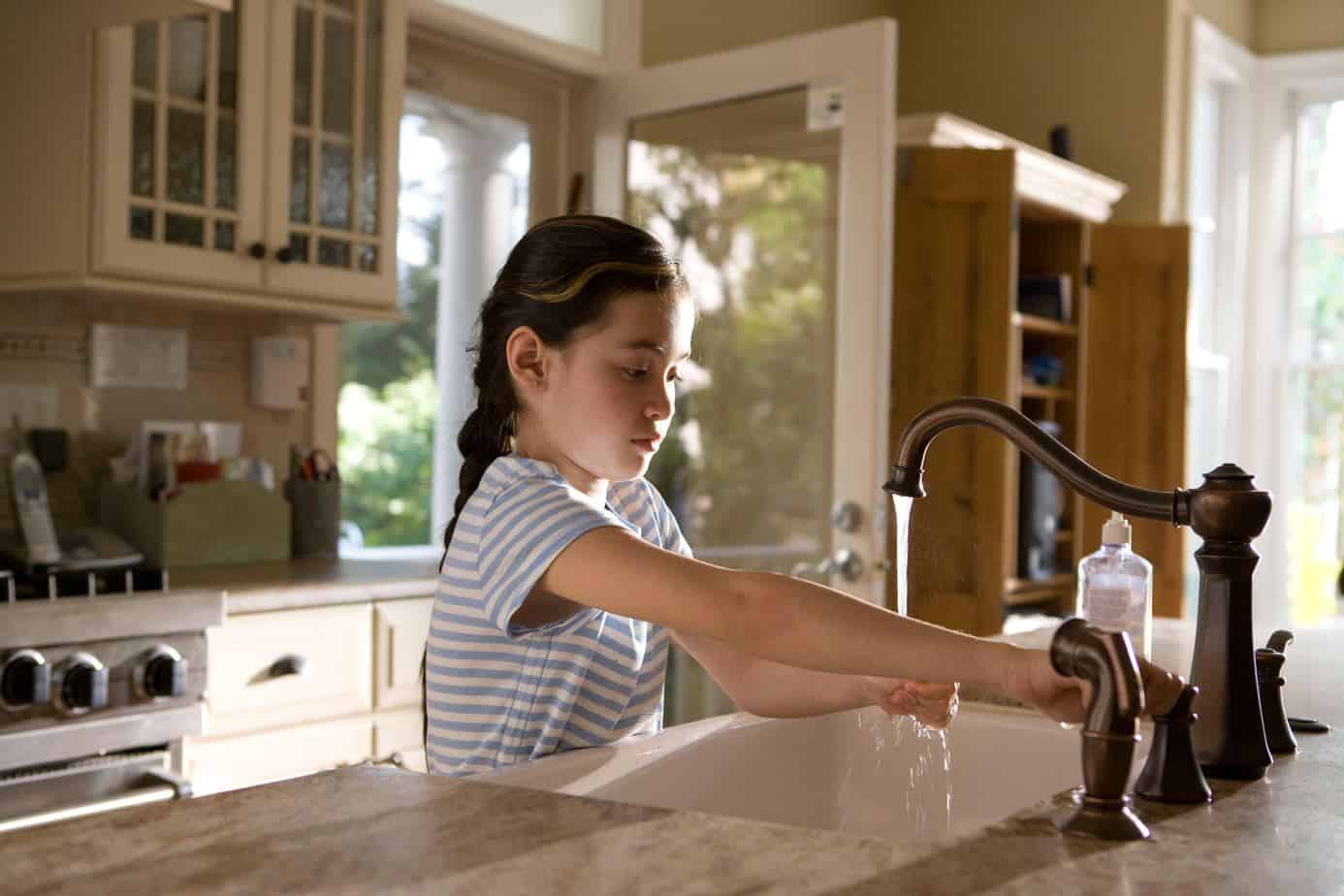 girl washing her hands in the kitchen sink