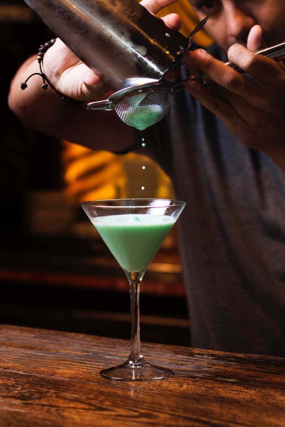 mint martini being strained into a martini glass.