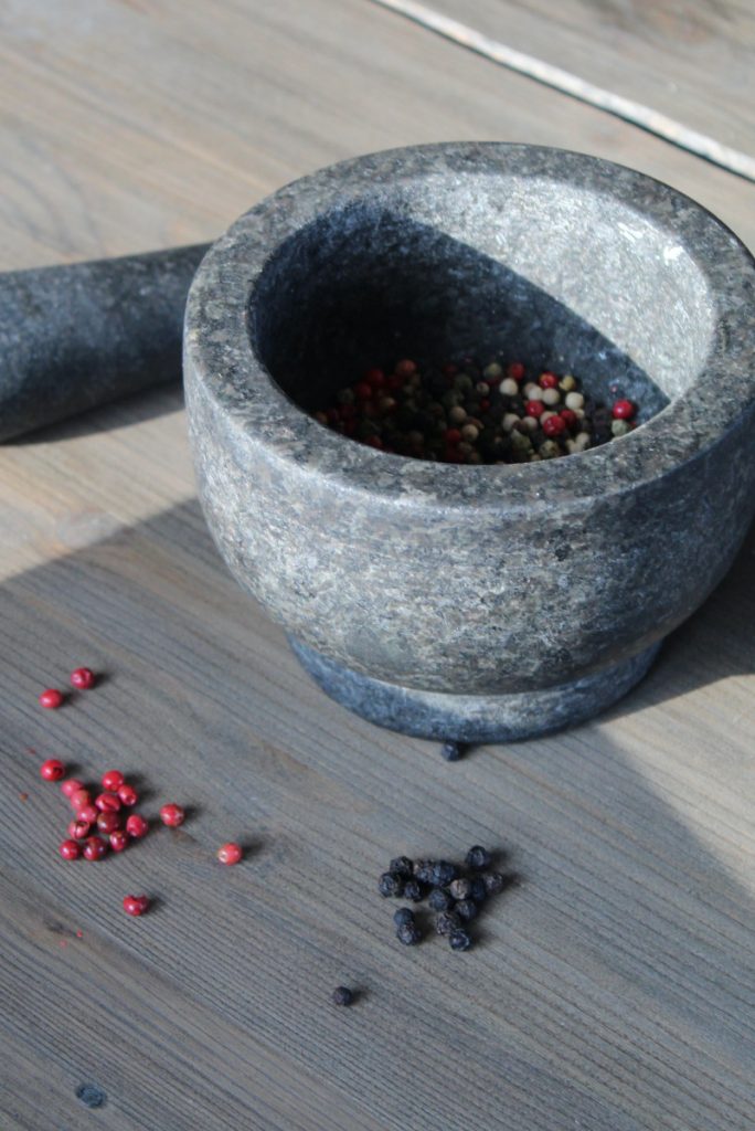 assorted colors of peppercorns in a mortar and pestle.