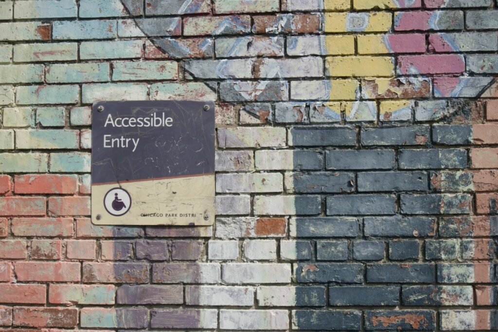 AWG Accessibility graphic featuring a black and white brick wall sign saying accessible entry.  