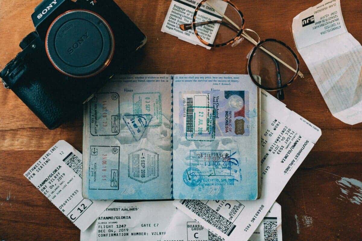 Camera passport glasses and boarding passes scattered on a table